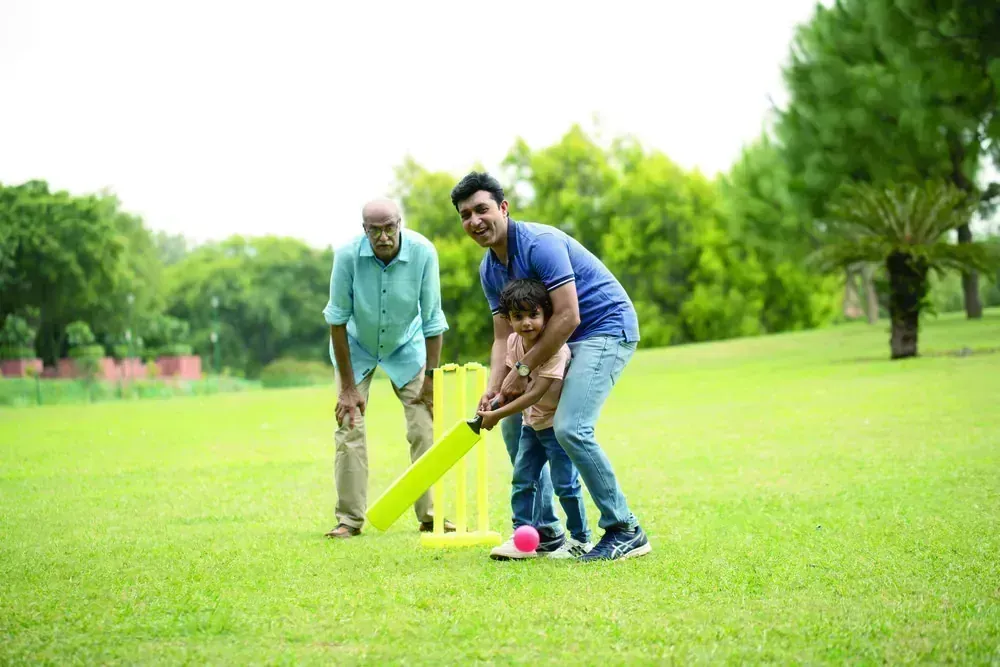 Three generations of a family playing cricket on the open lawn