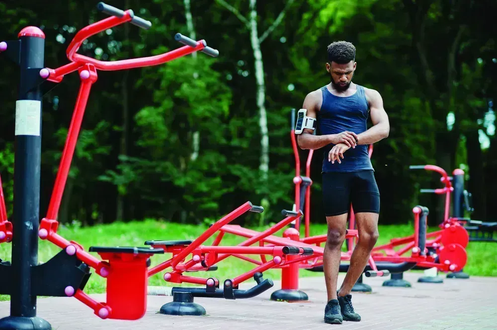 Outdoor gym equipment set on a paved deck against tree cover