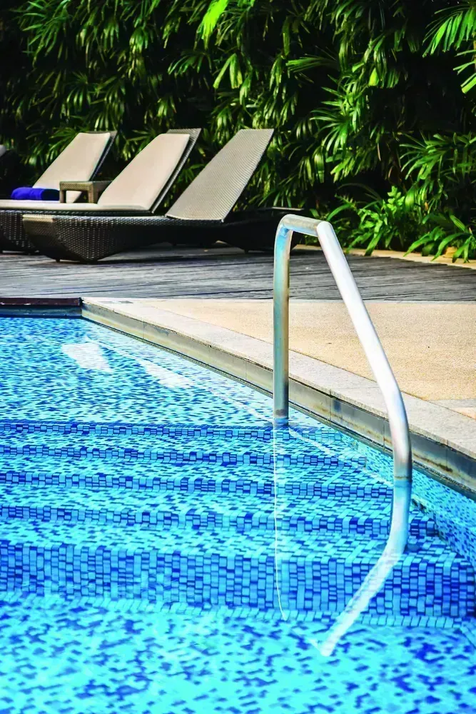 Pool deck with sun loungers against a planted green wall